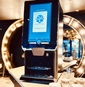 The Lua bean-to-cup coffee machine place on top of a counter displaying the 86 Degrees logo