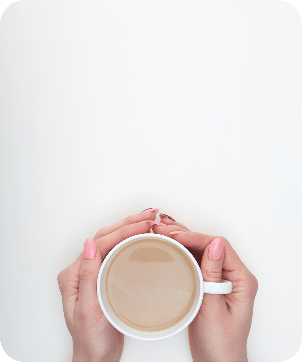 a person holds a latte coffee in two hands in front of neutral background