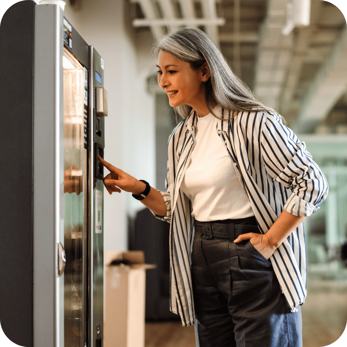 A lady selecting her choice of snack from an office vending machine.