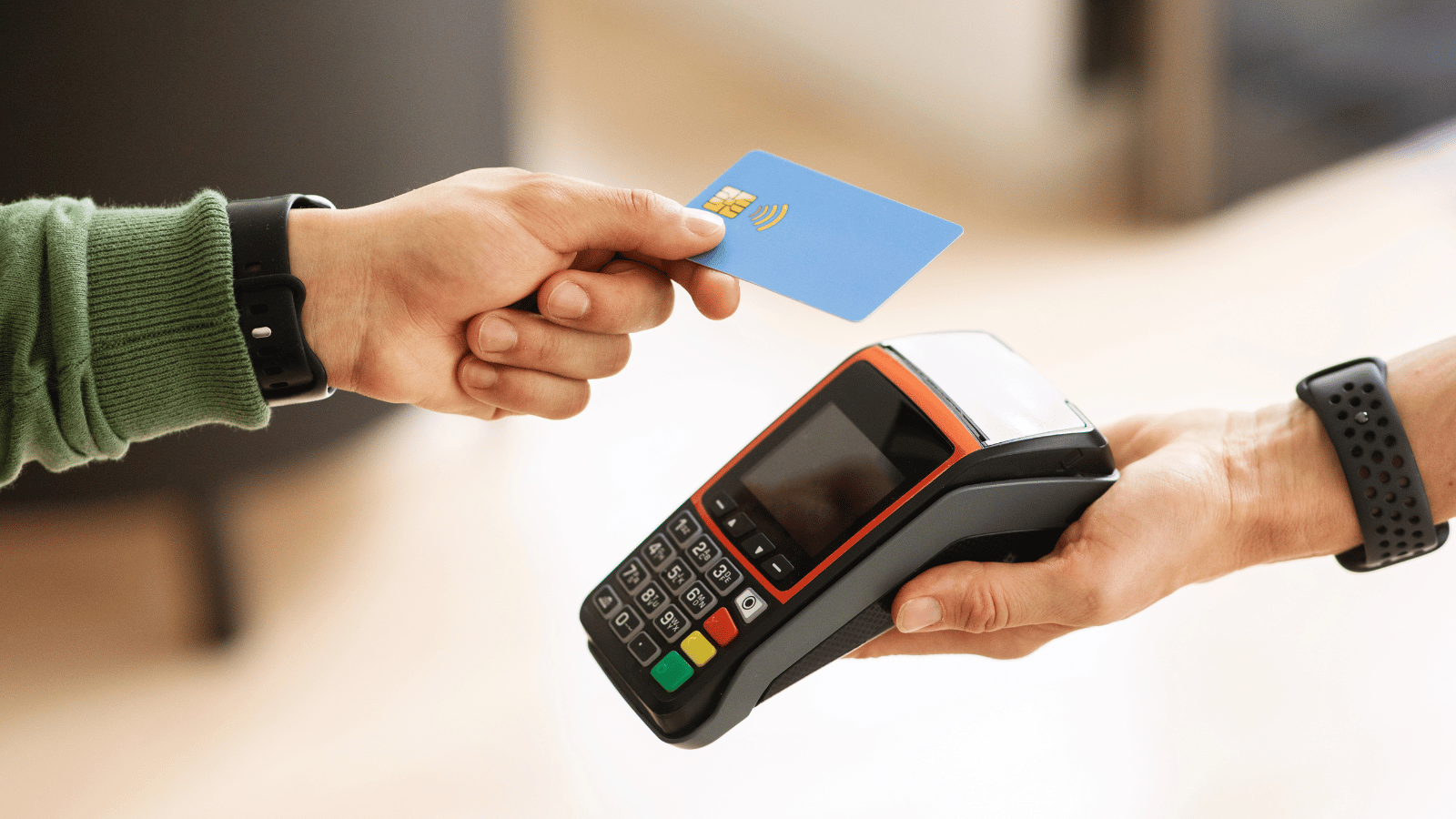 A person tabs their blue card against a card machine set up with a merchant cash advance.